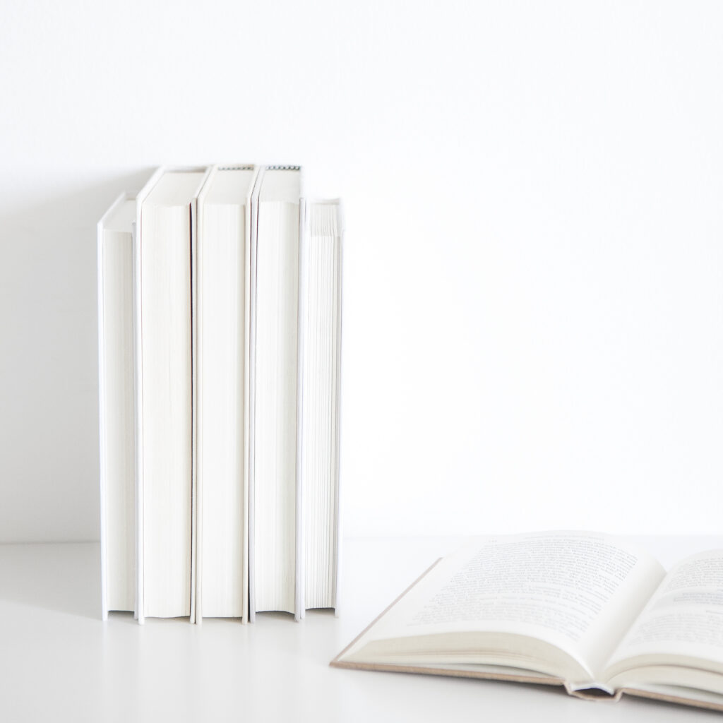 Three white books stacked against a wall, with an open book to the right highlighting affiliate marketing strategies